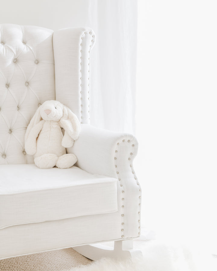 Close-up of the Baby Belle Ava Rocking Chair in white linen with diamond buttoning, studded armrest detail, and solid wood rocking base – styled in Jenna McArthur’s nursery