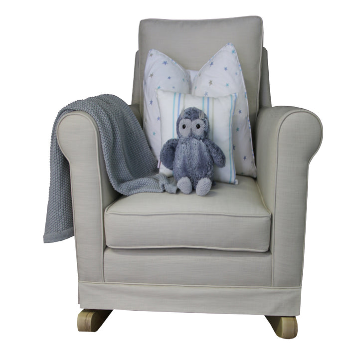 Tres Chic Rocking Chair in sand fabric with natural oak rocking legs, styled with grey throw, star-print cushions, and a soft owl plush toy.